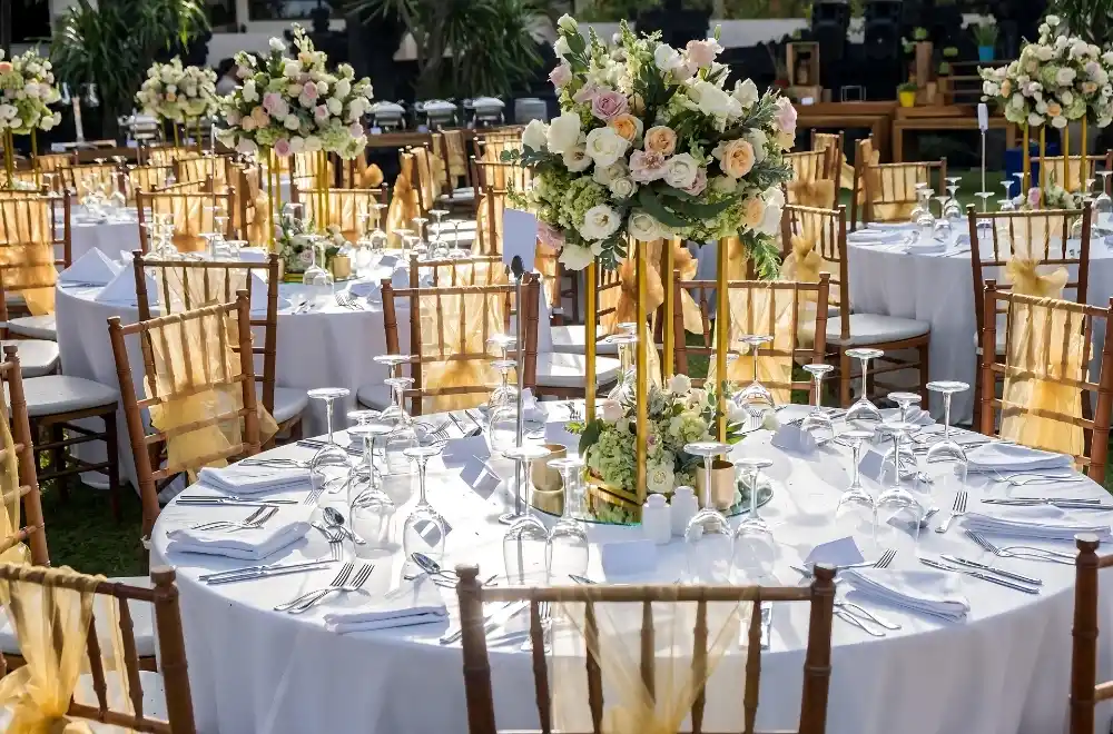 An outdoor wedding reception showcasing numerous tables and chairs set up for guests in a beautiful garden setting.