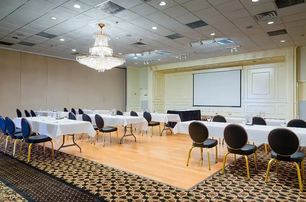 A spacious meeting room featuring multiple tables and chairs arranged for group discussions and presentations.