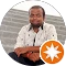 A man sits on steps, displaying a star emblem on his chest, exuding a sense of calm and contemplation.